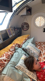 Cozy RV rental interior with a child resting on a colorful bed, framed photos, and camper decor.