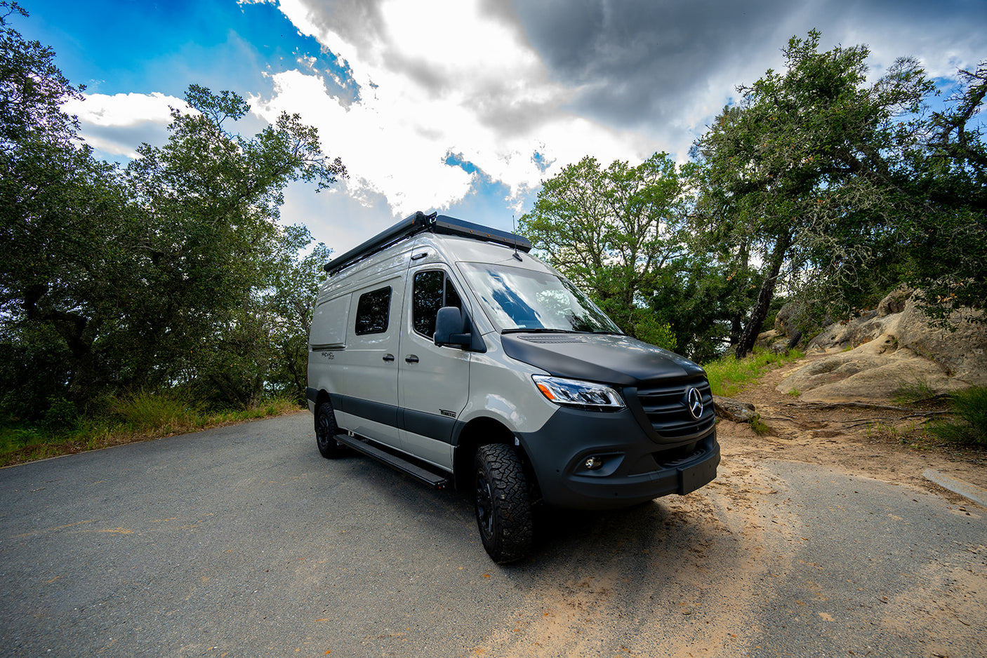 Ready for adventure! This custom Mercedes-Benz Sprinter rv rental is parked on a scenic road, surrounded by nature.