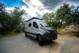 Ready for adventure! This custom Mercedes-Benz Sprinter rv rental is parked on a scenic road, surrounded by nature.