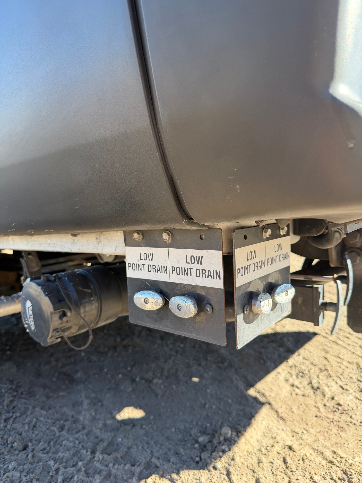 Low point drains and waste water connection on an rv rental, vital for draining and winterizing the recreational vehicle's plumbing.