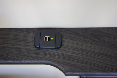 Close-up of a dual USB charging port with a yellow power indicator in an RV rental. Charge your devices easily.