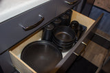 Open RV rental drawer reveals organized dark speckled cookware, cups, and utensils for easy camp kitchen use.