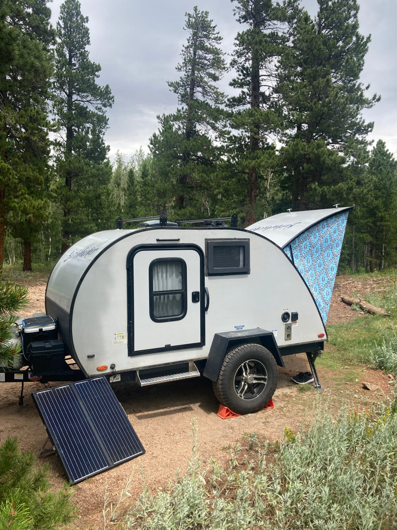 Enjoy an RV rental teardrop trailer with an extended awning and solar panel, parked in a serene forest campsite. — photo 11