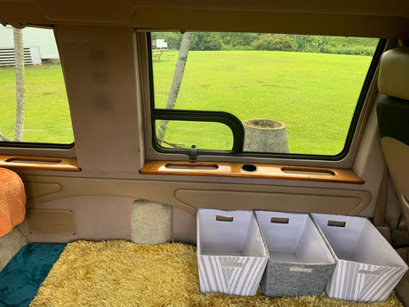 Cozy RV rental interior showing plush floor, green window view, and practical storage bins.
