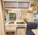 Step inside this RV rental's sleek kitchen and dinette, featuring a sink, stovetop, microwave, and fridge, all within a compact layout.