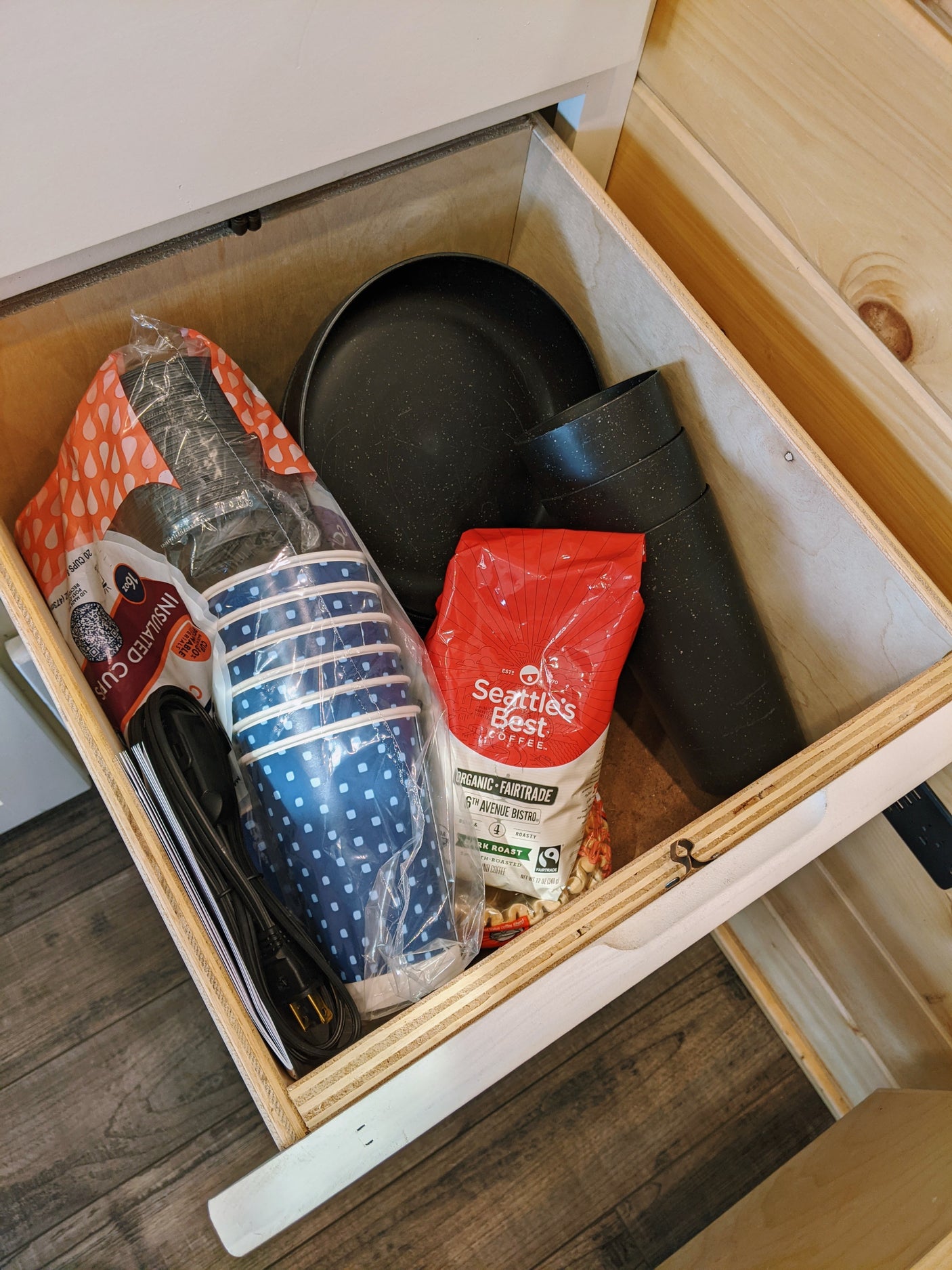 RV rental kitchen drawer stocked with Seattle's Best coffee, insulated cups, paper cups, and a cooking pan.
