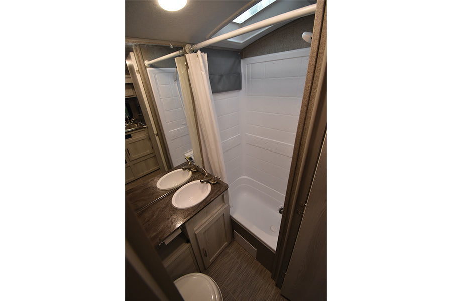 RV rental bathroom with modern double sinks, a clean shower, and toilet. Ideal for comfortable travel. — photo 18