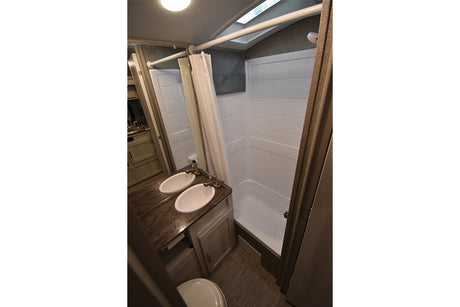 RV rental bathroom with modern double sinks, a clean shower, and toilet. Ideal for comfortable travel.