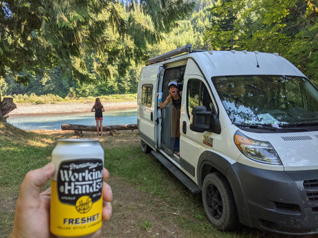 Outdoor fun with an RV rental! Excited people camping by a river, surrounded by lush forest. Van life adventures await!