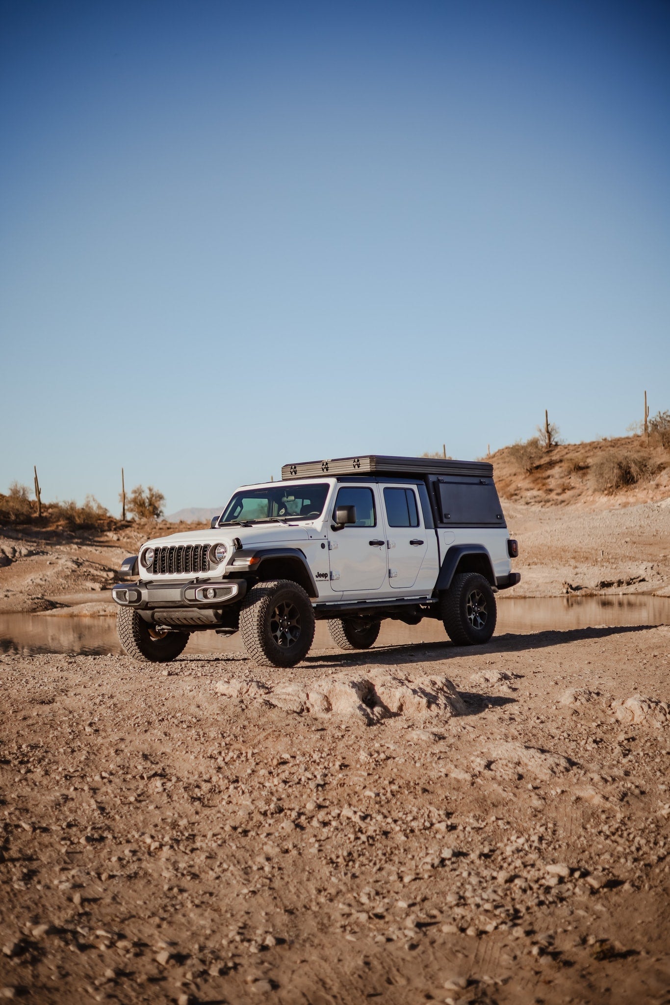 White Jeep Gladiator overlander with truck camper, perfect for rugged RV rental adventures by water in the desert. — photo 12