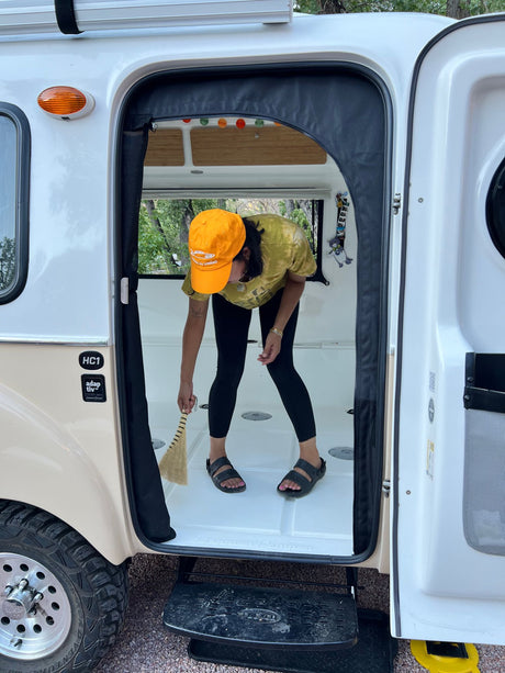 Daily chores in an RV rental. A person sweeps the camper's tidy interior, ready for more mobile living adventures.