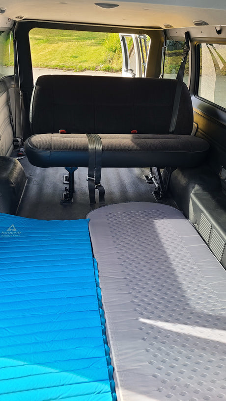 RV rental interior featuring a bench seat & two laid-out sleeping pads, ideal for comfortable van camping.