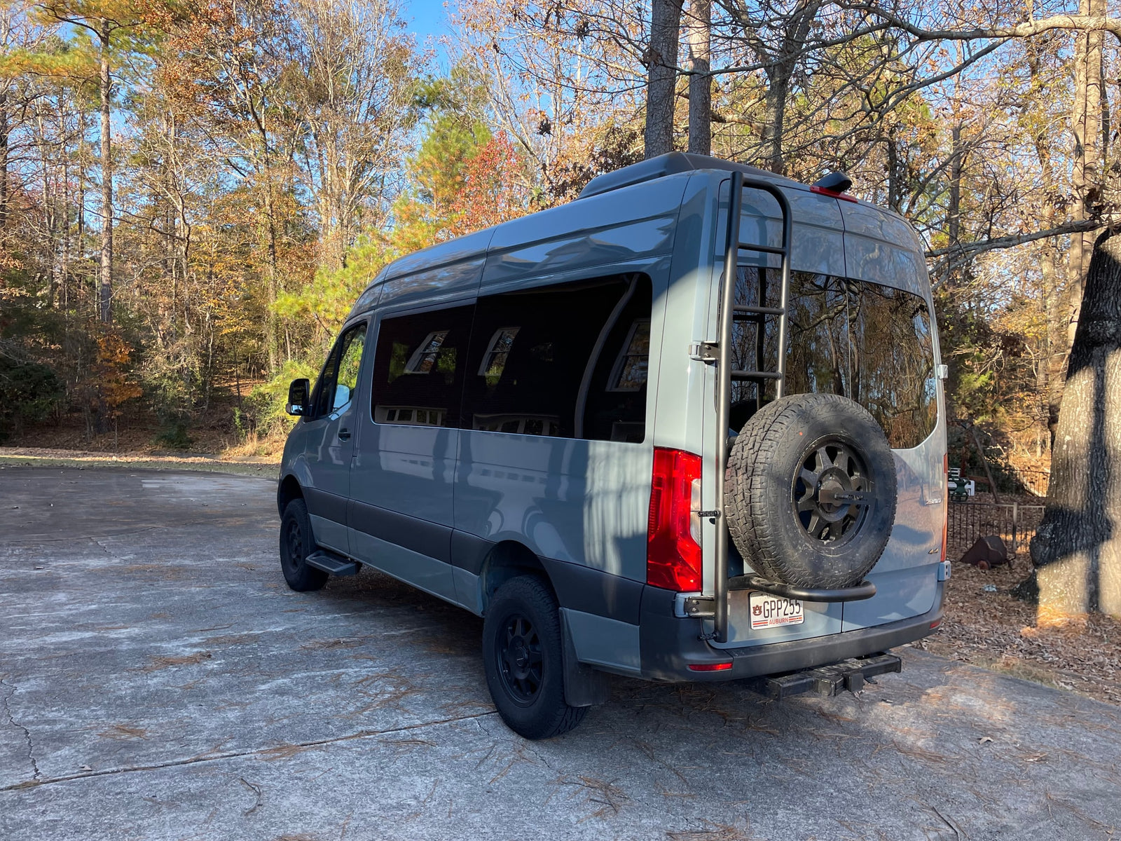  is parked on brown autumn leaves amidst green trees.|Inside a spacious passenger shuttle van