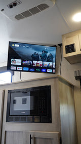 Modern RV rental interior: smart TV with streaming apps & integrated microwave above sleek cabinets.