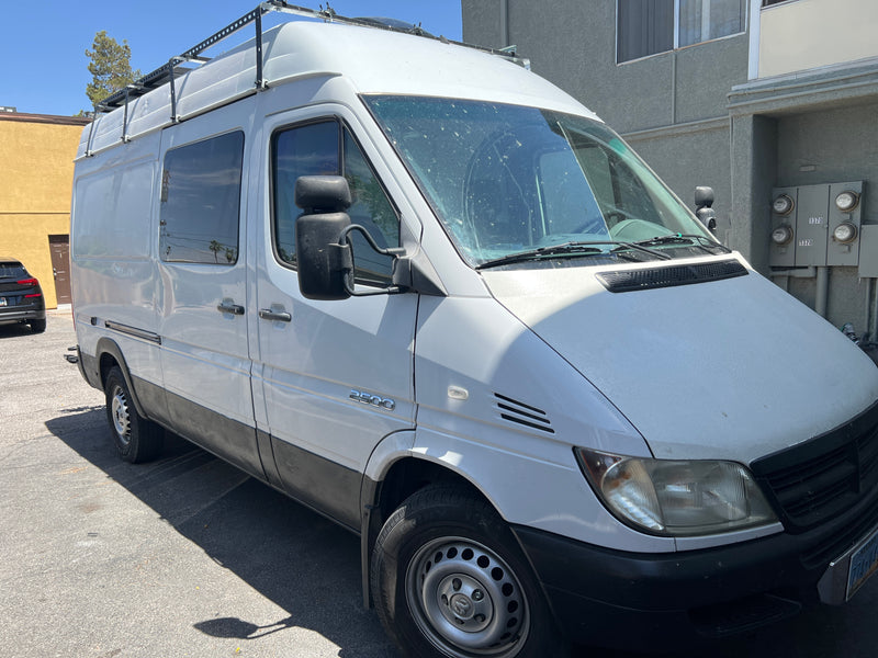 A white van with a roof rack, commonly used for an RV rental conversion, shows a '2500' badge and dirty windshield. — photo 9
