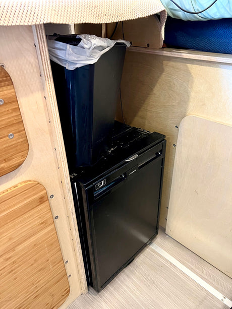 Compact Dometic refrigerator & trash can in an RV rental. Smart storage for a comfortable travel experience.