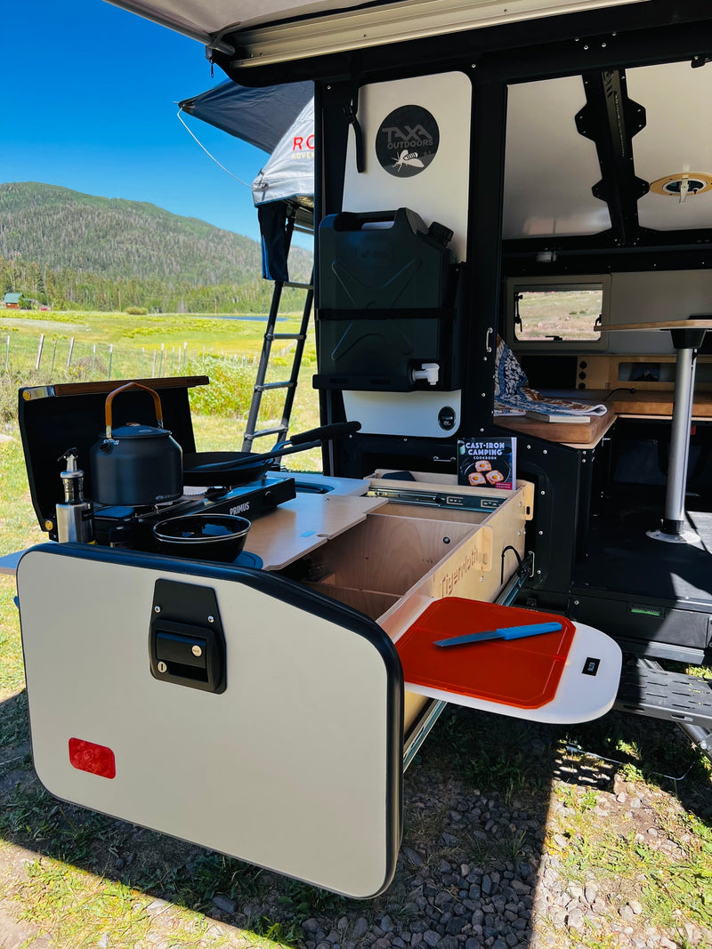 An RV rental's clever outdoor kitchen, featuring a Primus stove, kettle, and prep space, ready for cooking with mountain views. — photo 6