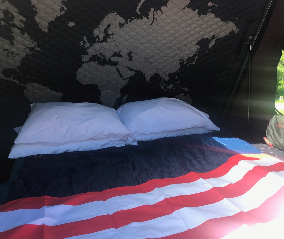 RV rental bed with white pillows, a patriotic blanket, & a quilted world map ceiling, perfect for travel. — photo 2