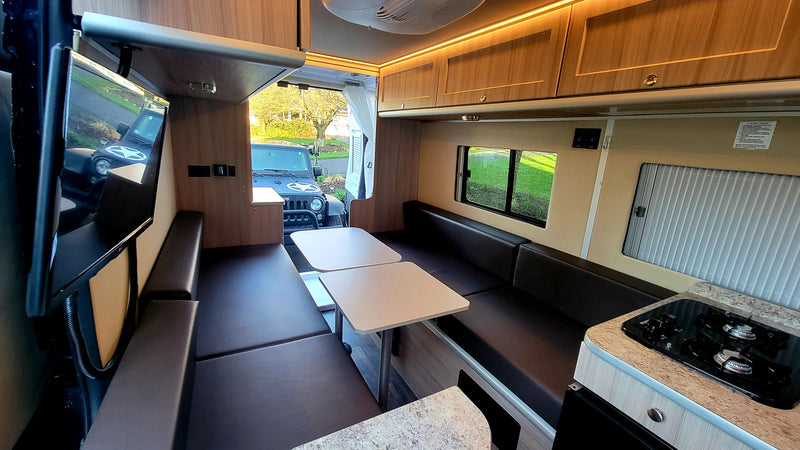 Modern RV rental interior with dinette, compact kitchen, convertible bed, and TV. Ideal for adventurous travelers. — photo 19