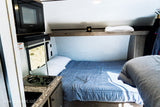 Inside this RV rental: a compact living area with bed, microwave, and stove for your travel comfort.