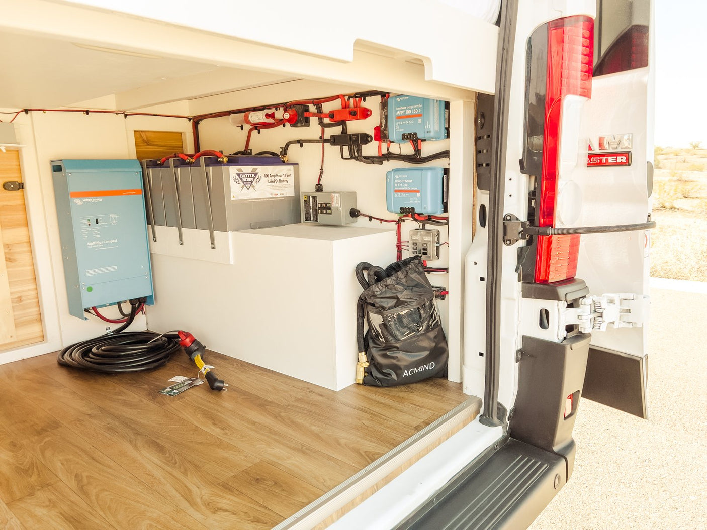 Inside an RV rental van, a robust power station features a Victron inverter, Battle Born LiFePO4 batteries, & solar charge controllers for off-grid living.