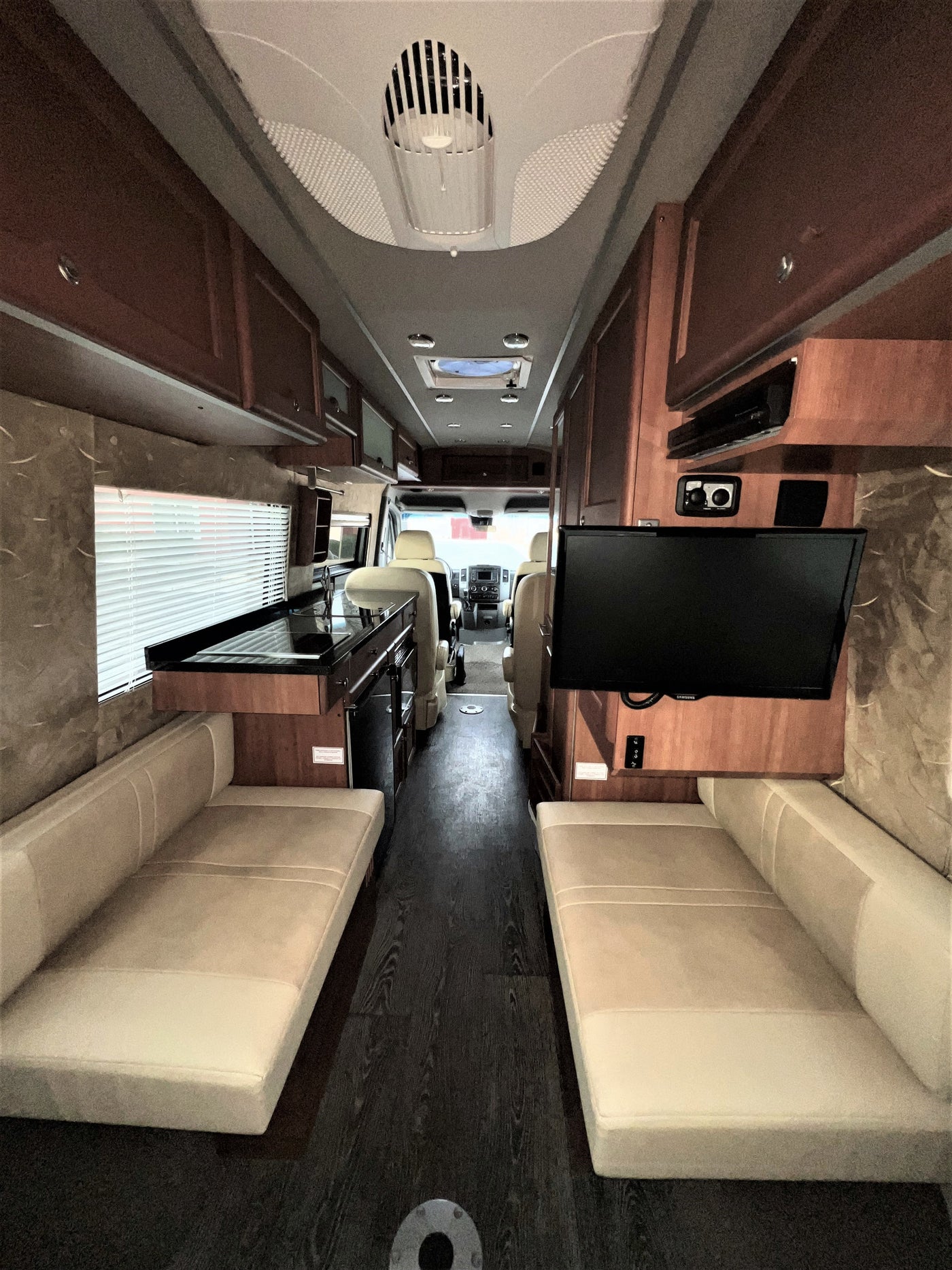 RV rental interior: galley kitchen, opposing benches, TV, and front driver's area in a clean, spacious layout. — photo 19