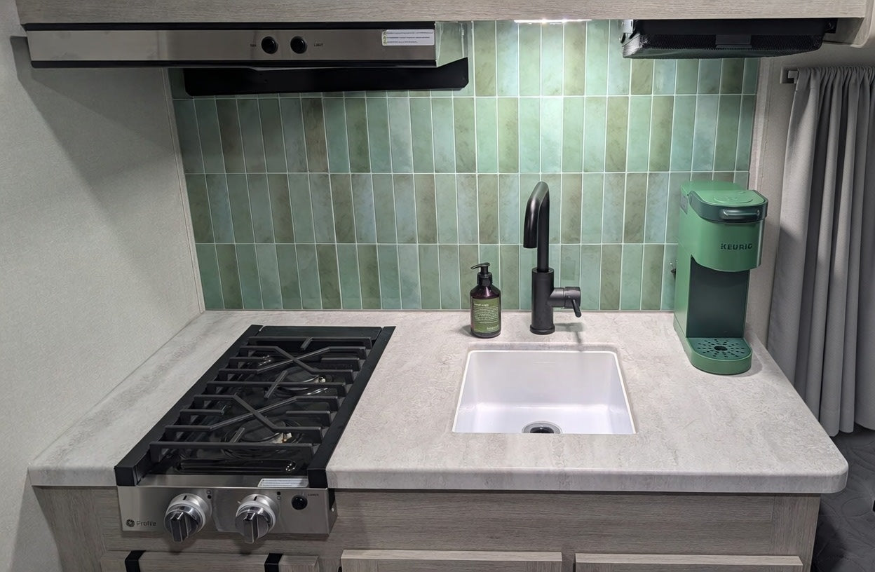  and light wood cabinetry for comfortable travel.|RV rental bedroom showing a bed with plaid sheets — photo 4