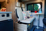 Relax in your RV rental! This camper van features cozy interior seating, a dining table, and a scenic window view for your travels.