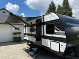 This Grand Design travel trailer, an excellent RV rental option, is parked on a paved driveway with its awning extended.