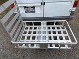 Hitch-mounted aluminum cargo carrier on RV rental van with ramp in upright position.