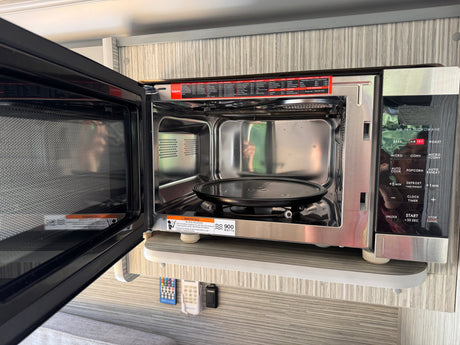This open Galanz 900-watt microwave and air fryer oven is ready for use in an RV rental, offering various cooking modes.