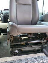 Interior of an RV rental showing a grey passenger seat, its metal frame, and patterned floor carpet.