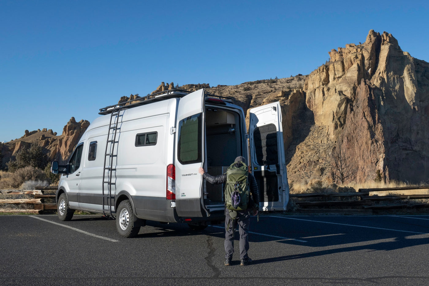 Adventure beckons! A person by an open silver Transit camper van at rocky cliffs. Ideal rv rental for exploration. — photo 18