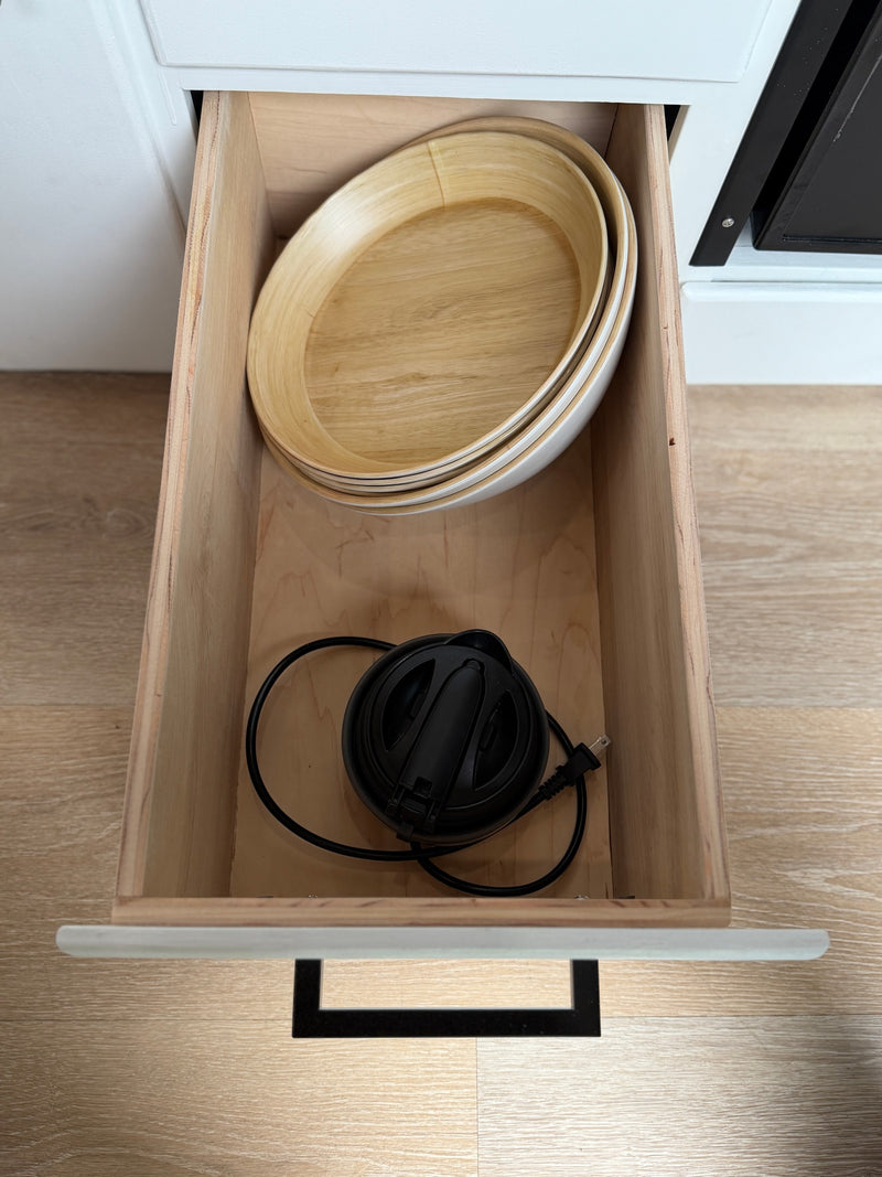 This RV rental's kitchen drawer is open, revealing stacked wooden bowls & a compact black electric appliance for convenient storage. — photo 13