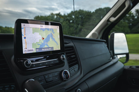 Spacious RV rental cabin view: modern dashboard with a large GPS map displaying Blue Springs, MO, and tactile controls.