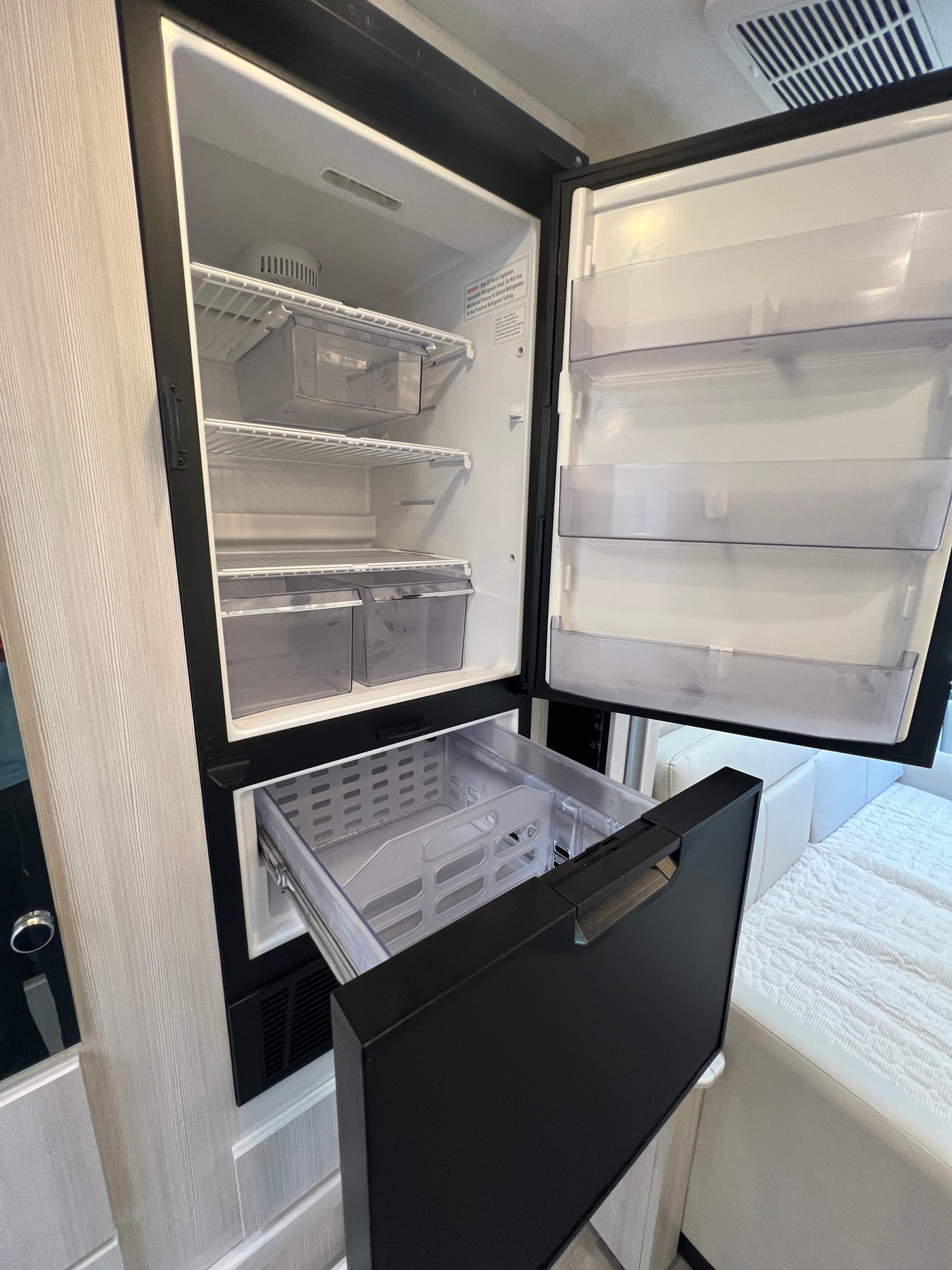 Open compact RV rental fridge and freezer drawer showing interior storage, shelves, and bins. — photo 18