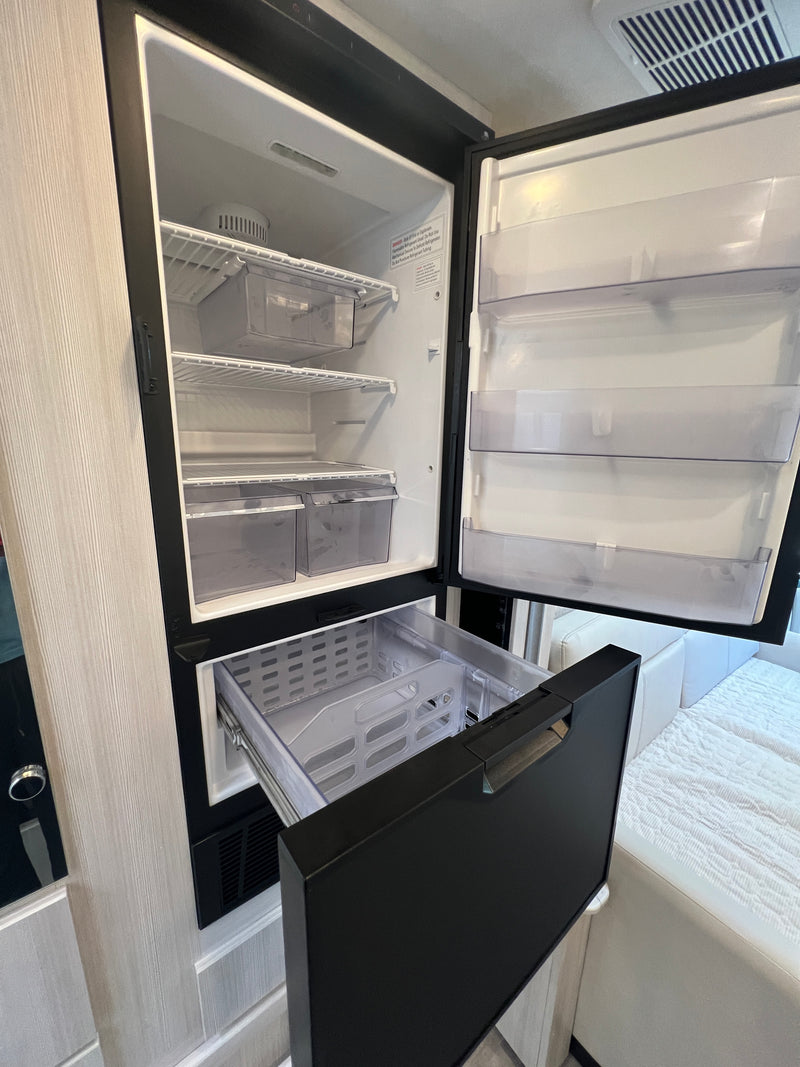 Open compact RV rental fridge and freezer drawer showing interior storage, shelves, and bins. — photo 18