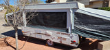 A grey and white Jayco pop-up camper, extended and set up outdoors, perfect for an rv rental getaway.