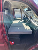 This RV rental’s front cab converts into a cozy sleeping space with a gray folding mattress, perfect for compact van adventures.