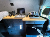 Moxie Van Co. RV rental: a compact camper van kitchen with a sink, induction cooktop, and under-counter refrigerator.