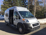 Silver Ram ProMaster camper van, with open side door. This RV rental is parked outdoors, ready for your next adventure.