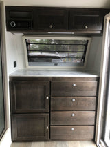 RV rental: Modern RV interior with dark wood cabinetry, a media system, ample storage, and bright countertop.