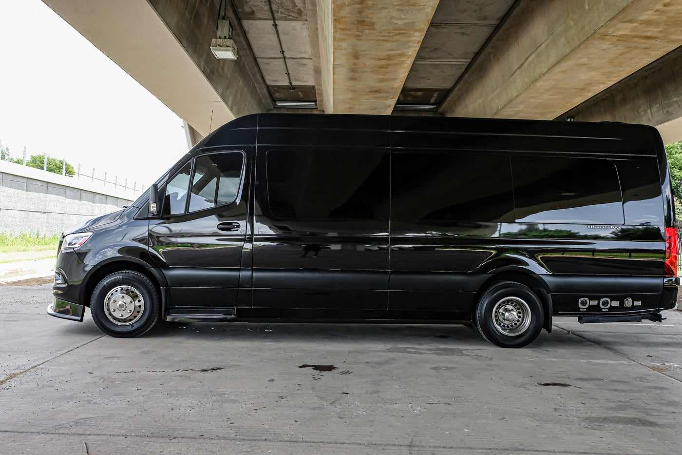 A sleek black Mercedes-Benz Sprinter luxury RV, ideal for rv rental, parked under a concrete overpass. — photo 15