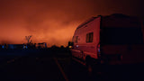 An RV rental (camper van) parked at night, bathed in the eerie orange glow of a smoky sky, with silhouetted trees.