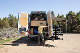 This RV rental camper van offers ultimate outdoor living! A man preps the integrated kitchen at the rear of the van.