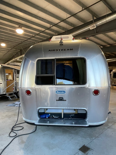 Rear view of a polished silver Airstream Bambi travel trailer, storage open. Perfect for your next RV rental adventure!