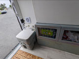 RV rental interior features a portable toilet, ventilation fan, and storage cabinets with bottled water.