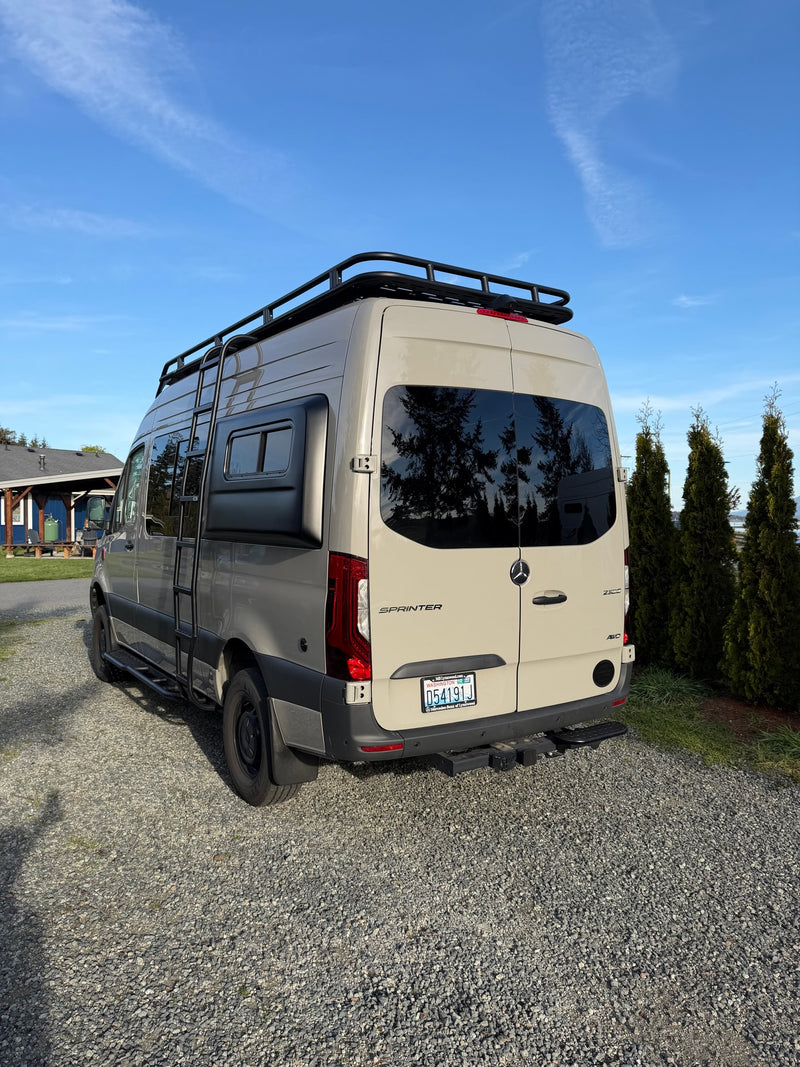 Tan Mercedes Sprinter camper van for rv rental, featuring a roof rack and ladder, parked on gravel. — photo 13