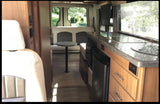 Inside this modern RV rental: a well-equipped kitchen, cozy dining area with rear views, and comfortable front seating.