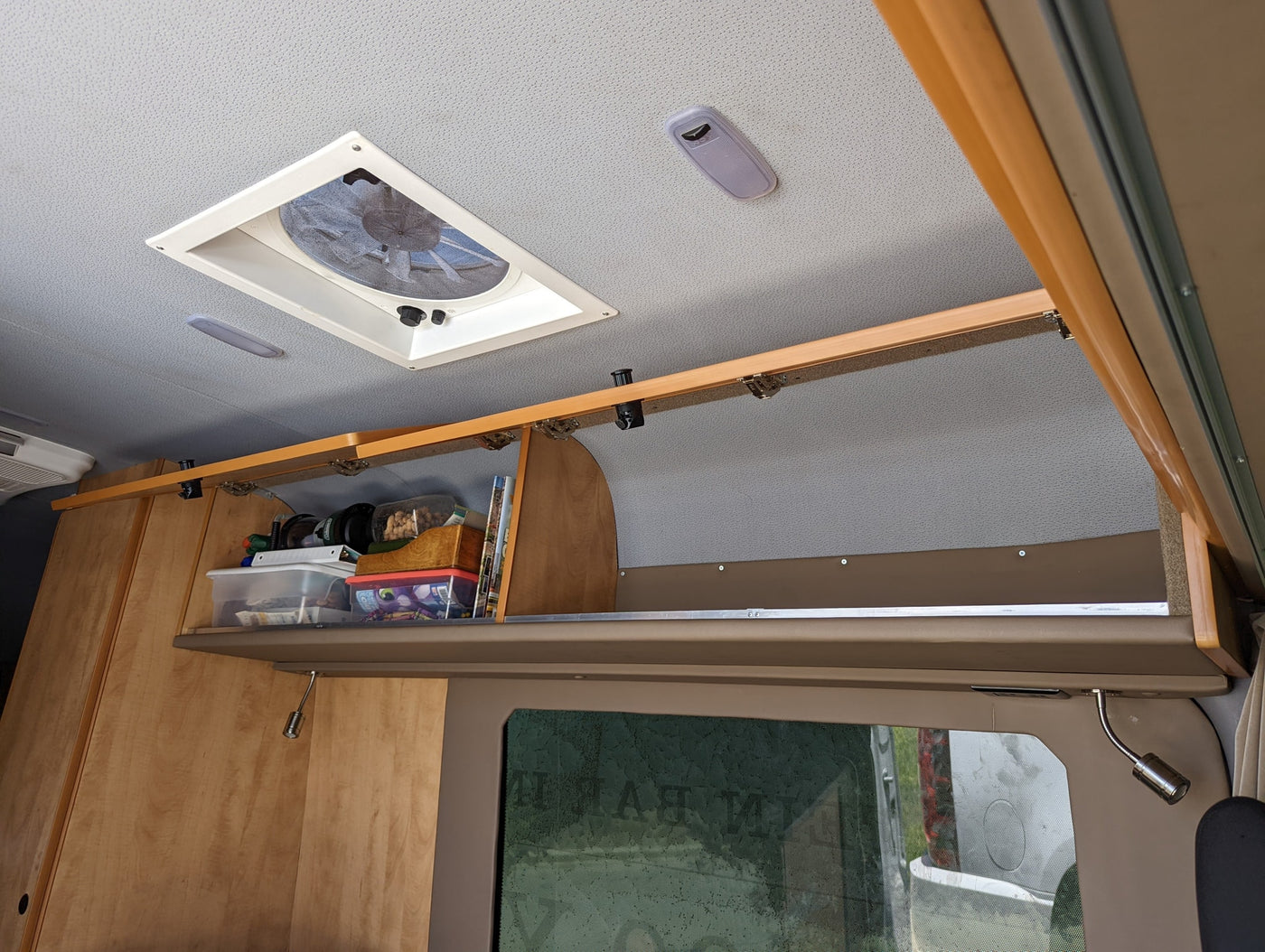 Overhead view inside an RV rental, featuring a ceiling fan, lights, and open storage for essentials. — photo 15